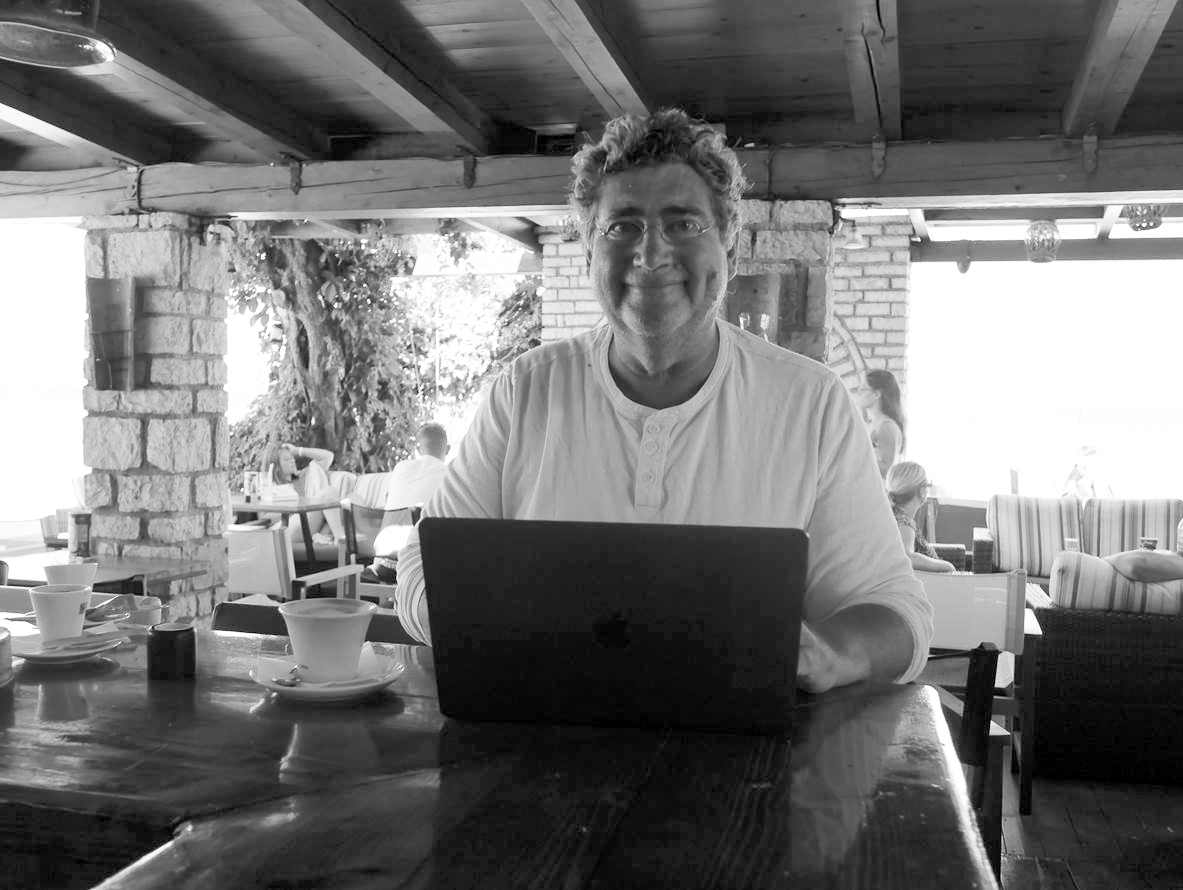 Der Autor Detlef Jens arbeitet an seinem Laptop und lächelt für das Portrait freundlich in die Kamera